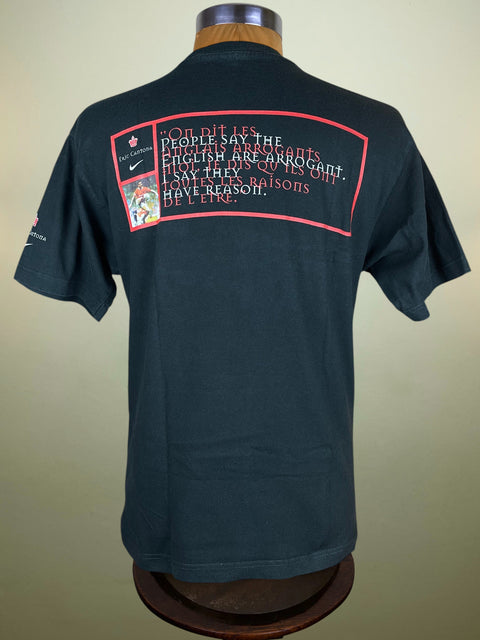 Black t-shirt with text and graphics on a mannequin against a beige background