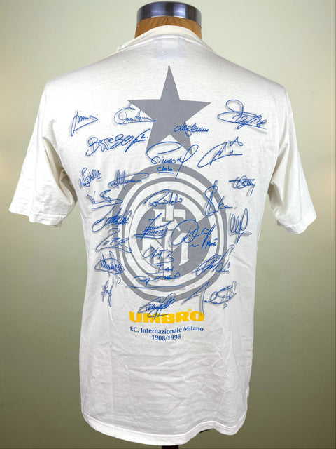 A white short-sleeve T-shirt displayed on a mannequin torso, showing the back side with the Inter Milan logo circular logo, covered in blue autograph signatures, with yellow 'UMBRO' text near the bottom.