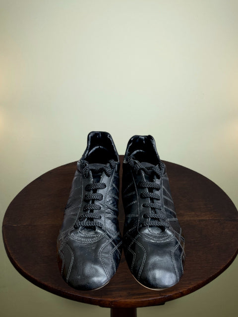 A Roberto Baggio's match worn black soccer boots placed on a wooden table against a plain background.