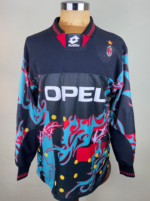 A black, blue, red, and yellow soccer jersey with a vibrant, geometric pattern, featuring the AC Milan logo and a star logo.