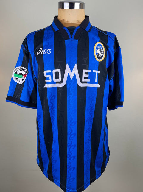 Blue and black striped Atalanta 1996-97 jersey with SoMet branding on a mannequin against a gray background
