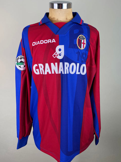 Red and blue Bologna 1997-98 jersey with brand logos on a mannequin against a gray background